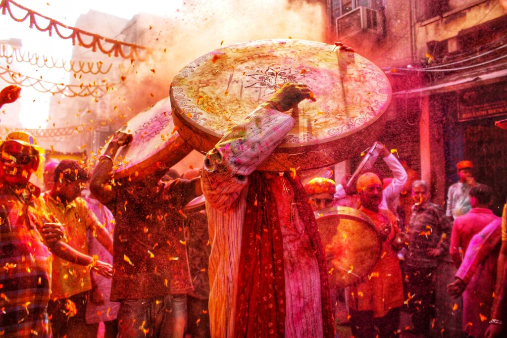 A lively scene of people celebrating the Holi festival in Kolkata with colors and traditional drums.